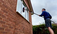 Man cleaning windows at a house in Maghull, Merseyside